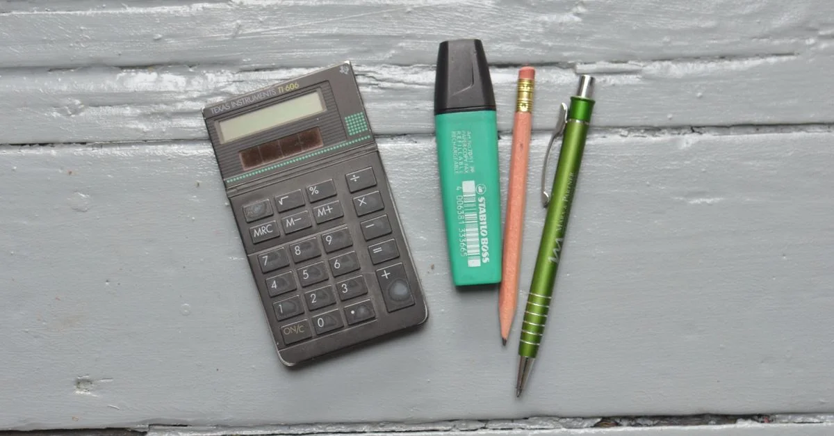 Vue de dessus d'une calculatrice, d'un marqueur, d'un crayon et d'un stylo sur un bureau en bois. Idéal pour des thèmes d'affaires ou d'éducation.