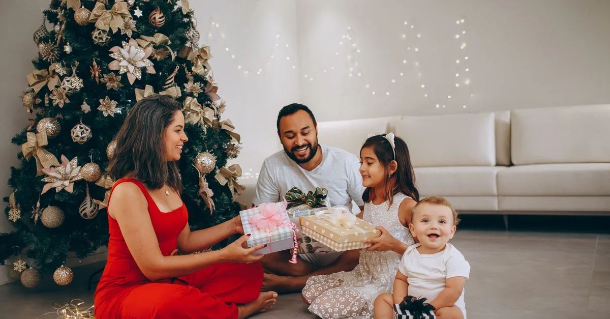 Une famille joyeuse échangeant des cadeaux près de l'arbre de Noël, capturant des moments festifs à l'intérieur.