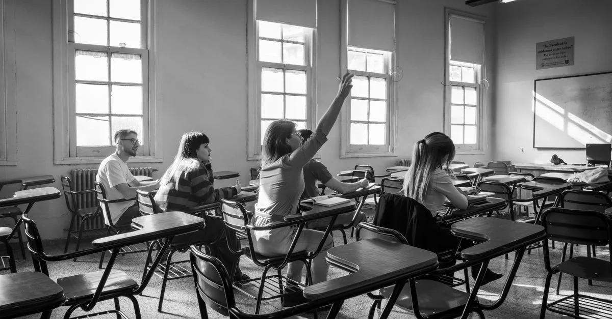 Des élèves en classe pendant un cours, l'un d'eux levant la main.