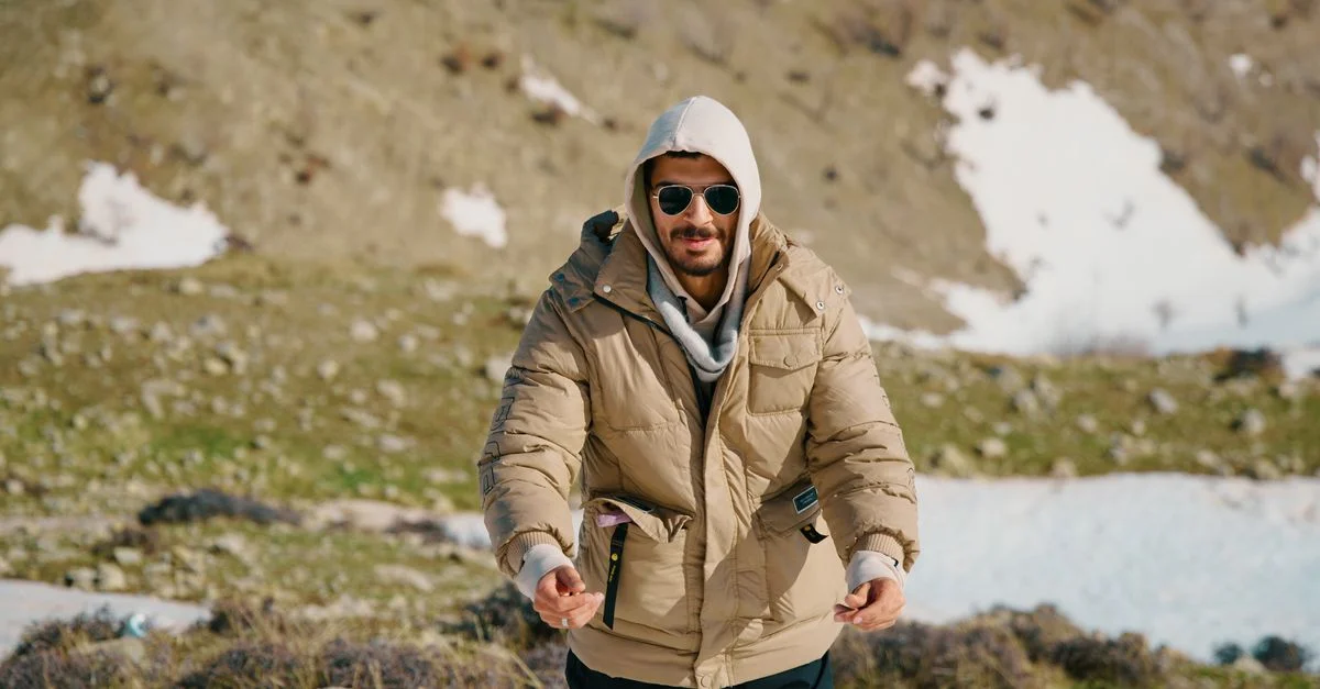 Un homme portant des vêtements d'hiver fait de la randonnée dans un paysage montagneux enneigé.