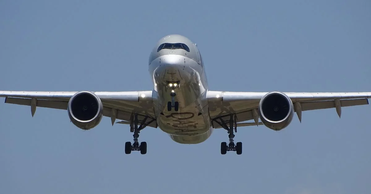 Une vue frontale époustouflante d'un avion commercial en vol contre un ciel bleu clair.