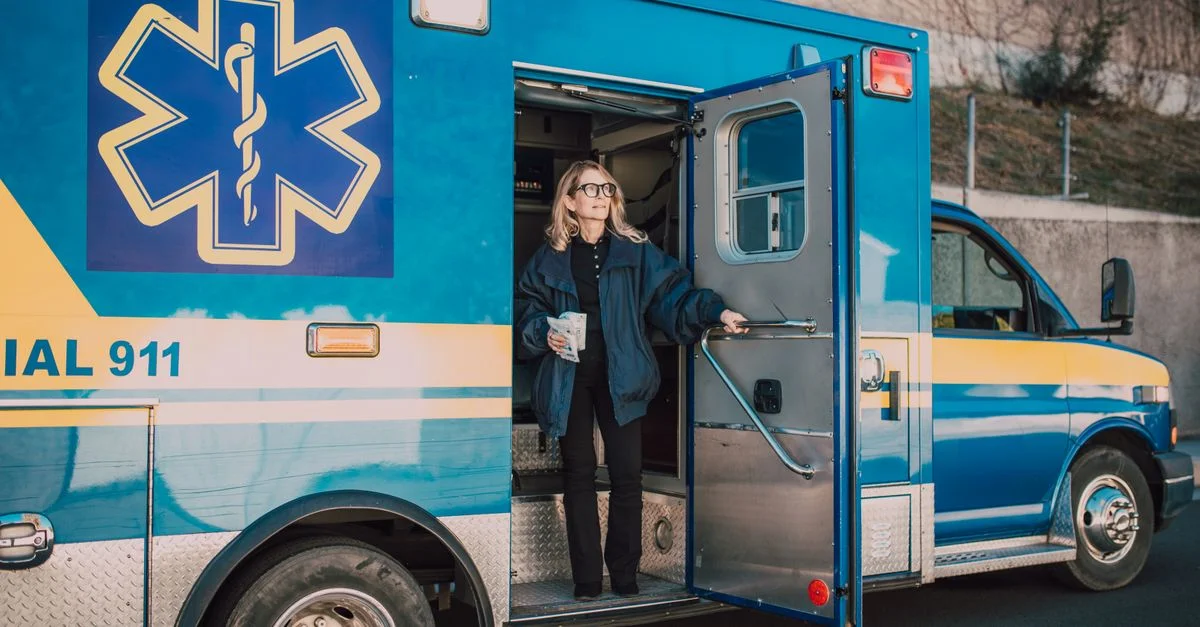 Paramédic féminine avec un café debout près de l'ambulance pendant la journée.