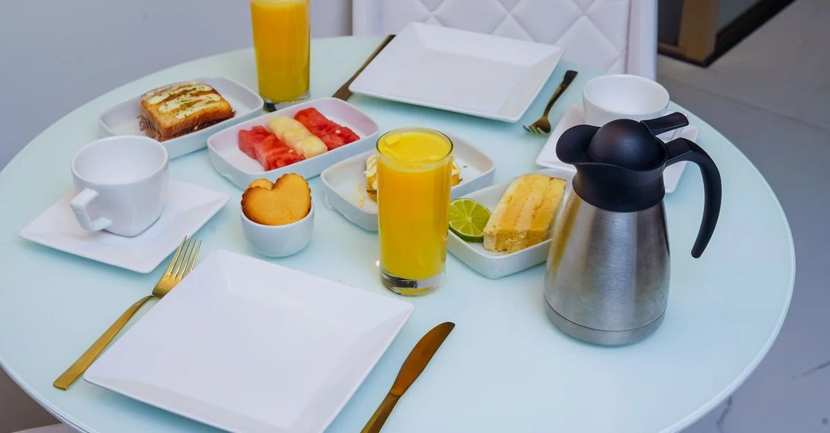 Une table de petit-déjeuner stylée avec des pâtisseries, des fruits frais et du jus d'orange dans un cadre intérieur moderne.